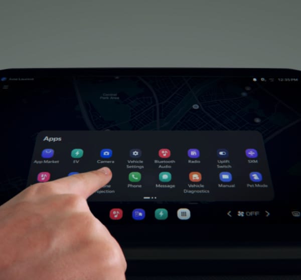 Ein Finger berührt den Touchscreen des Infotainmentsystems, auf dem ein App-Menü im Fahrzeug angezeigt wird.